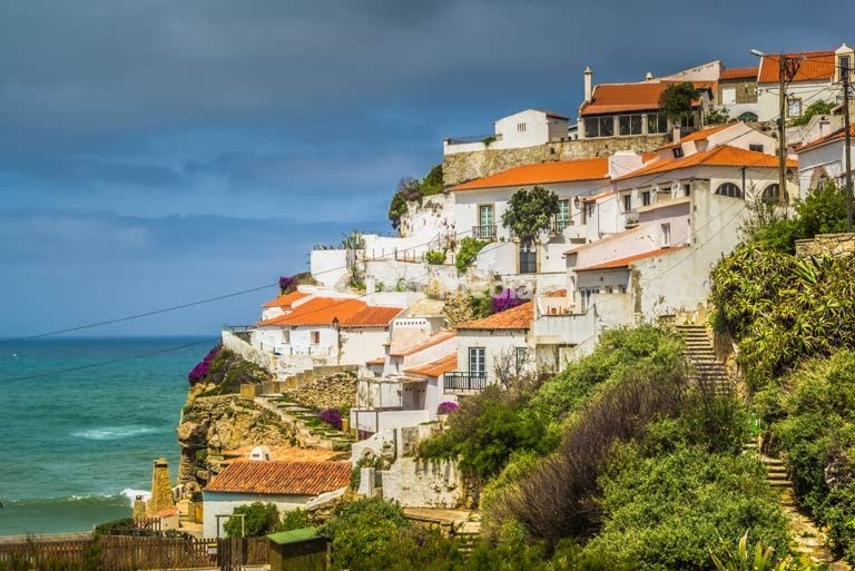 Picturesque coastal village Azenhas do Mar perched on cliffs above Atlantic waters near Sintra, Portugal with terracotta tile rooftops