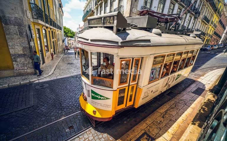 Historic Tram 24 on cobblestone tracks at Praça de Camões with traditional colorful buildings in Lisbon, Portugal public transport