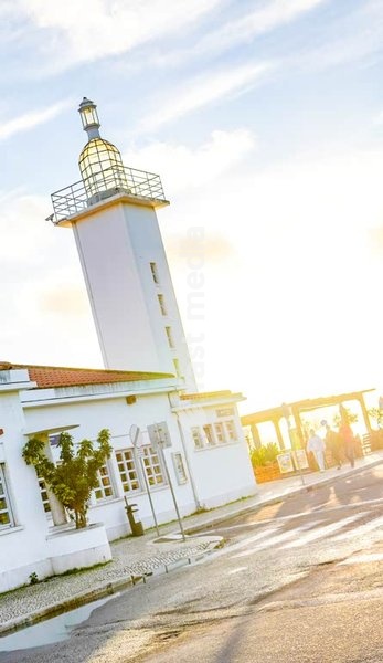 Historic Belém ferry station lighthouse tower with golden sunlight, Lisbon waterfront maritime architecture Portugal tourism landmark