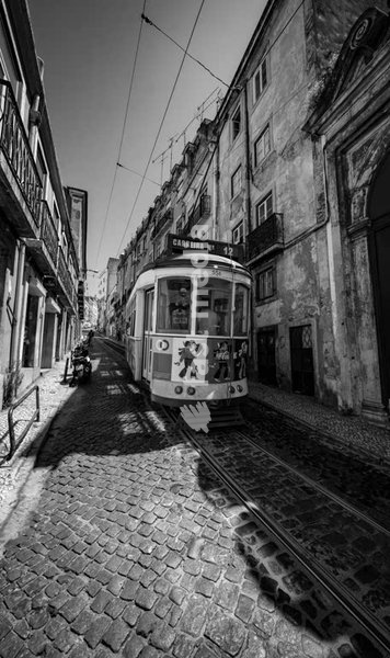 Historic Lisbon tram on cobblestone street in old city quarter, black and white vintage Portugal public transport photography
