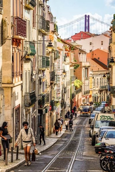 Narrow cobblestone street with traditional colorful buildings and historic street lamps in Lisbon's old town, Portugal.