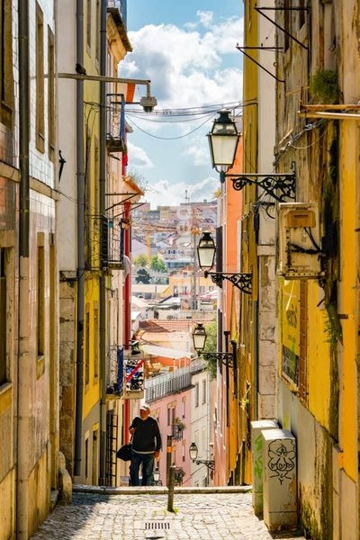 Narrow cobblestone street with traditional colorful buildings and historic street lamps in Lisbon's Bairro Alto district