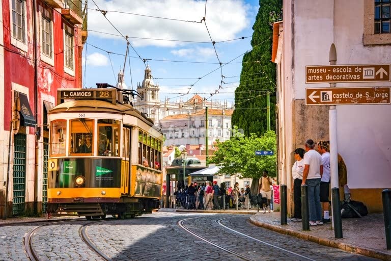 Historic Tram 28E on cobblestone streets in Lisbon's old Alfama district, Portugal. Sao Vicente church in the back.
