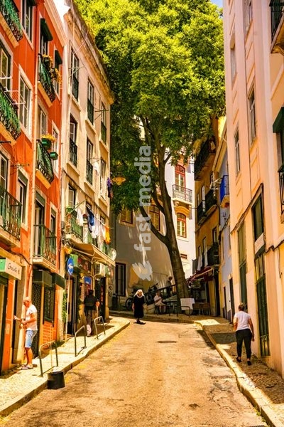 Steep narrow street with traditional colorful buildings in Lisbon's old town, Portugal