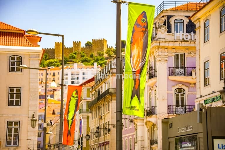 Sardine flags on Rossio Square with the historic castle visible on the hilltop behind colorful Lisbon buildings