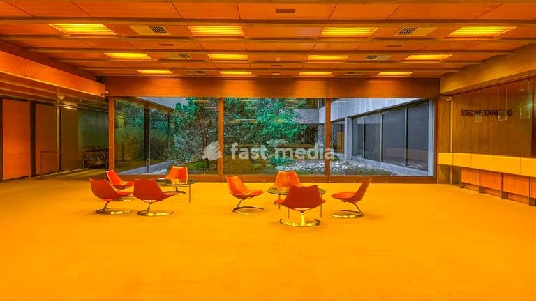 Mid-century modern interior of Gulbenkian Foundation featuring iconic orange swivel chairs and floor-to-ceiling windows, Lisbon, Portugal
