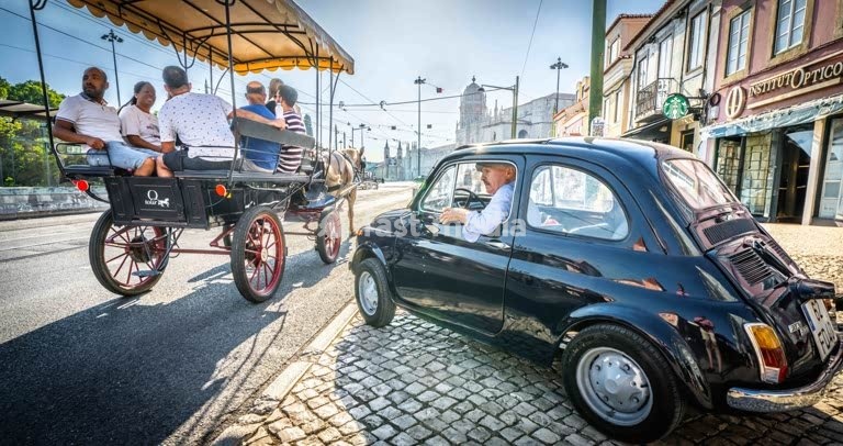 Vintage Fiat 500 and horse-drawn tourist carriage on cobblestone streets in historic Belém district, Lisbon, showcasing traditional transport