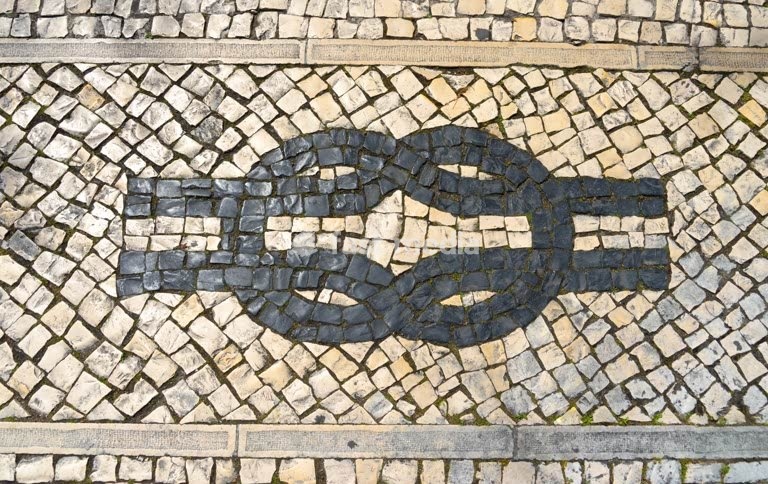 A figure-eight knot as a nautical symbol in the white cobblestones of a pavement in Lisbon harbour, Portugal