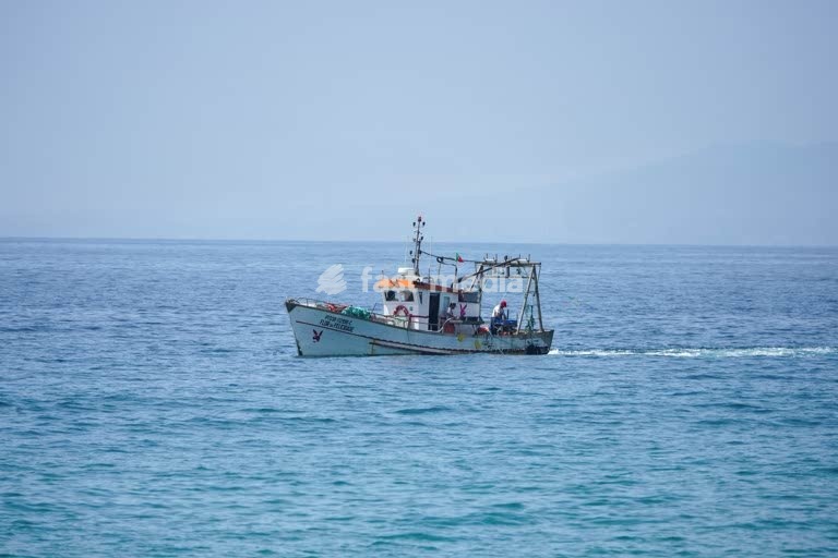 Fishing boat off the Portuguese coast in the Atlantic Ocean. Traditional vessel with fishermen at work on a clear summer day