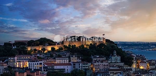 Panoramic elevated view of Lisbon historic center and Church of St Stephen overlooking Tagus River during pink sunset