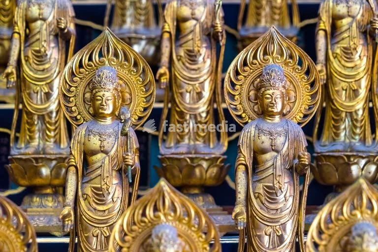 Golden Buddha statues with ornate aureoles and lotus thrones displayed on Buddhist altar in temple in Nagoya, Japan showing religious artistry
