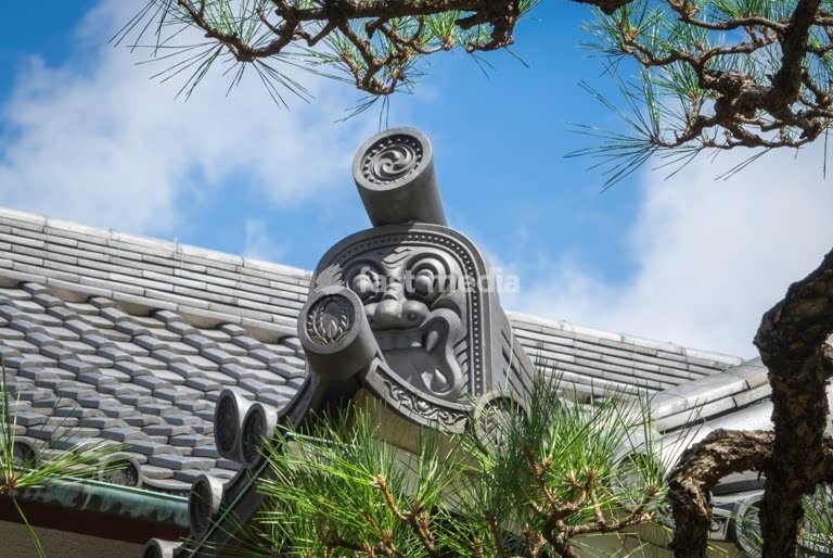 Traditional Japanese temple roof, Nagoya, Japan, ornate oni roof tile framed by pine branches and blue summer sky