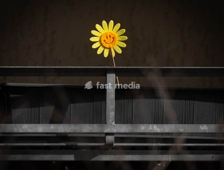 Smiling felt sunflower on dark balcony