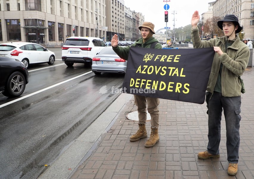 Two activists holding the "Free Azovstal Defenders" banner gesture at passing cars in Khreshchatyk Street during the weekly “Don’t Stay Silent! Captivity Kills” rally in support of Ukrainian military personnel held in Russian captivity or listed as missing in action in Maidan Nezalezhnosti…