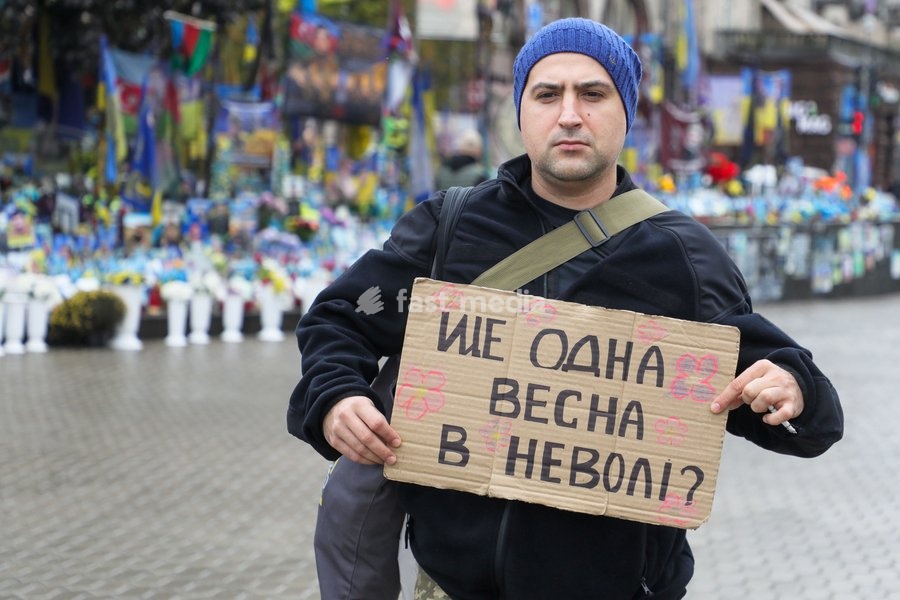 An activist holds a placard reading "Another Spring in Captivity?" while standing outside a memorial in Maidan Nezalezhnosti (Independence Square) during the weekly “Don’t Stay Silent! Captivity Kills” rally in support of Ukrainian military personnel held in Russian captivity or listed as missing…