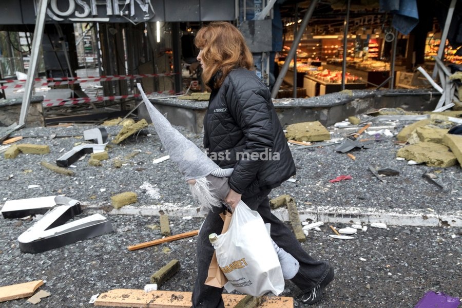 A woman carries a bag and a Christmas gnome as she walks through debris outside a confectionery shop in the Solomianskyi district is damaged by a Russian attack, Kyiv, Ukraine, October 19, 2026. During the night and morning, Russia launched a massive strike on the capital using ballistic missiles,…