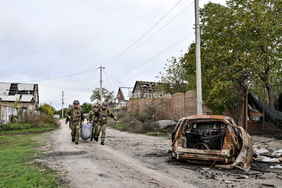 Zaporizhzhia police officers and a family member carry an elderly bedridden woman in a blanket towards a car during an evacuation from the front-line settlement of Komyshuvakha, Zaporizhzhia region, Ukraine, October 19, 2026