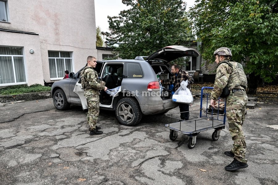Zaporizhzhian police officers and an evacuated man unload personal belongings from a car at a transit centre in Zaporizhzhia, Ukraine, October 19, 2026. A family with an elderly woman with limited mobility was evacuated from the frontline settlement of Komyshuvakha