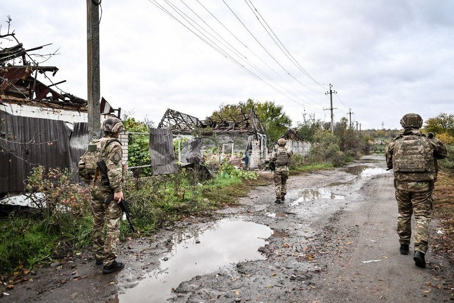 Armed Zaporizhzhia police officers walk along a street during a humanitarian mission to evacuate a family with an elderly woman with low mobolity from the front-line settlement of Komyshuvakha, Zaporizhzhia region, Ukraine, October 19, 2026