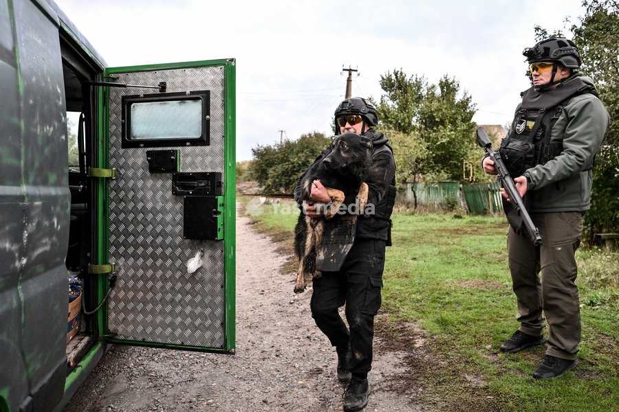 A volunteer carries a rescued dog to a minibus during a humanitarian evacuation mission in the front-line settlement of Komyshuvakha, Zaporizhzhia region, Ukraine, October 19, 2026