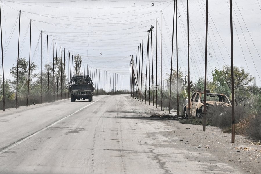 A Ukrainian armoured vehicle drives along a road covered with an anti-drone net towards a car carrying Zaporizhzhia police officers who evacuated a family, including an elderly woman with limited mobility, from the front-line settlement of Komyshuvakha to a transit centre in Zaporizhzhia,…