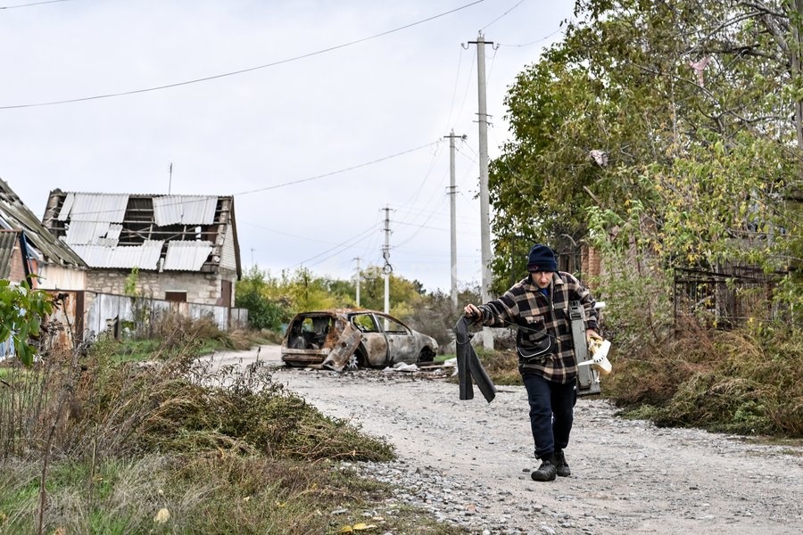 A local man carries everyday items to a car during a humanitarian evacuation mission for his family from the front-line settlement of Komyshuvakha, Zaporizhzhia region, Ukraine, October 19, 2026