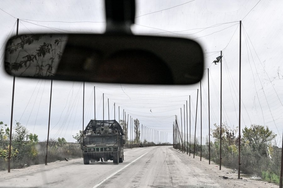 A Ukrainian armoured vehicle drives along a road covered with an anti-drone net towards a car carrying Zaporizhzhia police officers who evacuated a family, including an elderly woman with limited mobility, from the front-line settlement of Komyshuvakha to a transit centre in Zaporizhzhia,…