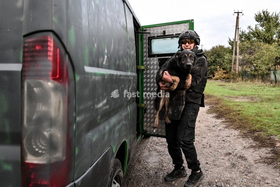 A volunteer holds a rescued dog near a minibus during a humanitarian evacuation mission in the front-line settlement of Komyshuvakha, Zaporizhzhia region, Ukraine, October 19, 2026