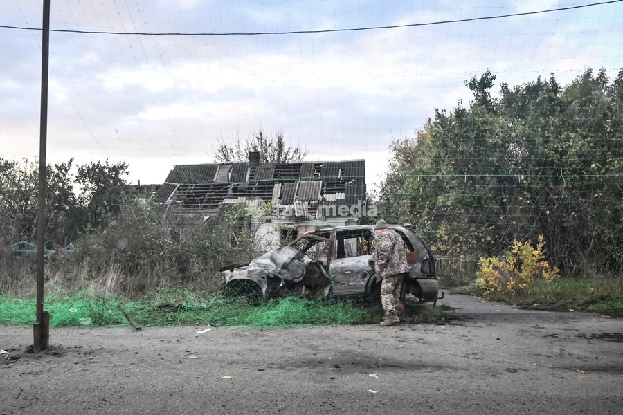 A man stands by a civilian car destroyed by a Russian bombardment outside a ruined house in the front-line settlement of Komyshuvakha, Zaporizhzhia region, Ukraine, October 19, 2026