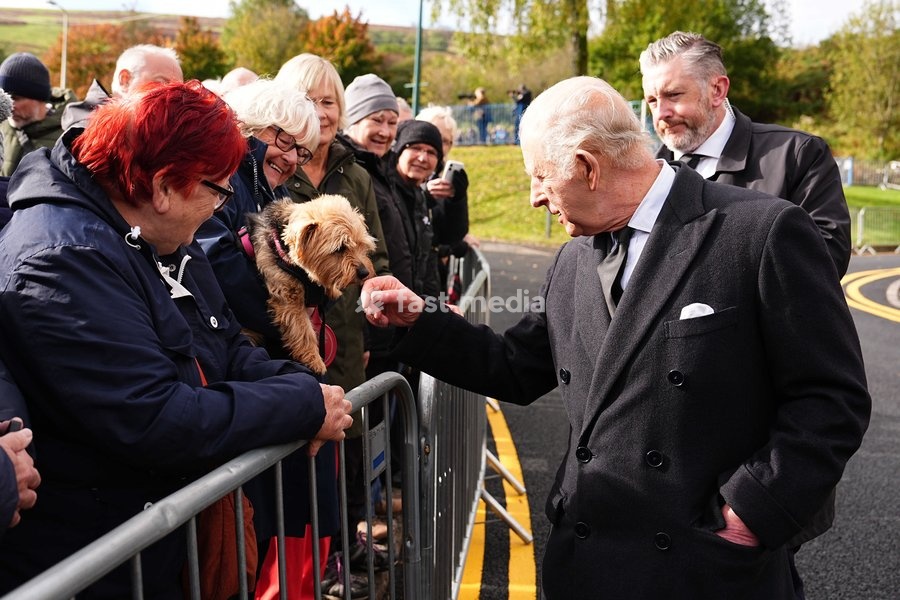 King Charles III pets a dog held by one of the members of the public lining the streets outside Aberfan Memorial Garden, where survivors, bereaved parents and members of the community are paying tribute to the 144 people who lost their lives in the Aberfan disaster on October 21 1966. Picture date:…