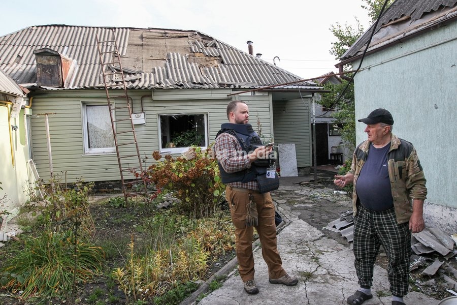 Two men talk outside a house damaged by a Russian attack in Dnipro, Ukraine, October 22, 2026. According to city head Borys Filatov, 11 private houses were damaged in the strike on Thursday morning, and one home burned down completely