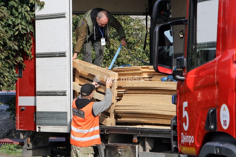 Men unload planks near houses damaged by a Russian attack, Dnipro, Ukraine, October 22, 2026. According to city head Borys Filatov, 11 private houses were damaged in the strike on Thursday morning, and one home burned down completely