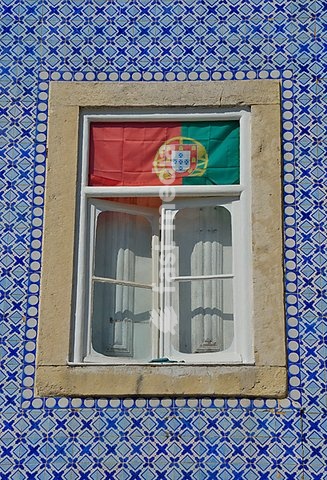 House facade with azulejos wall tiles and the Portuguese flag in the window, historic city district