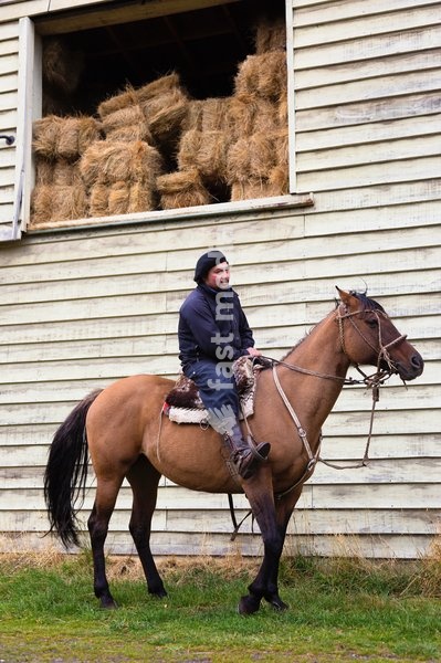 Gaucho on horse in front of stables. Patagonia. Chile