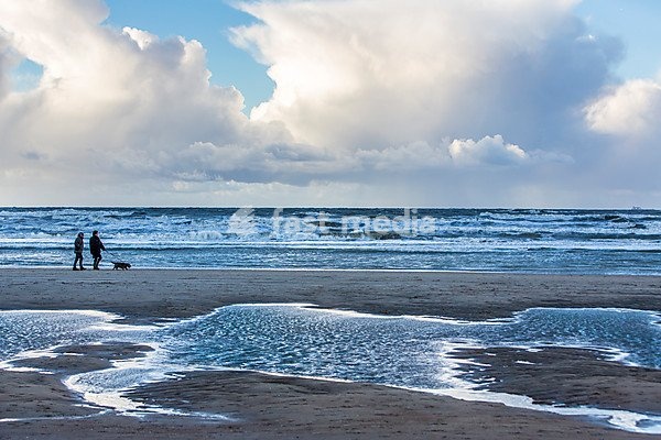 Walkers, North Sea beach, stormy sea, stormy clouds during an autumn storm, De Haan, Flanders, Belgium