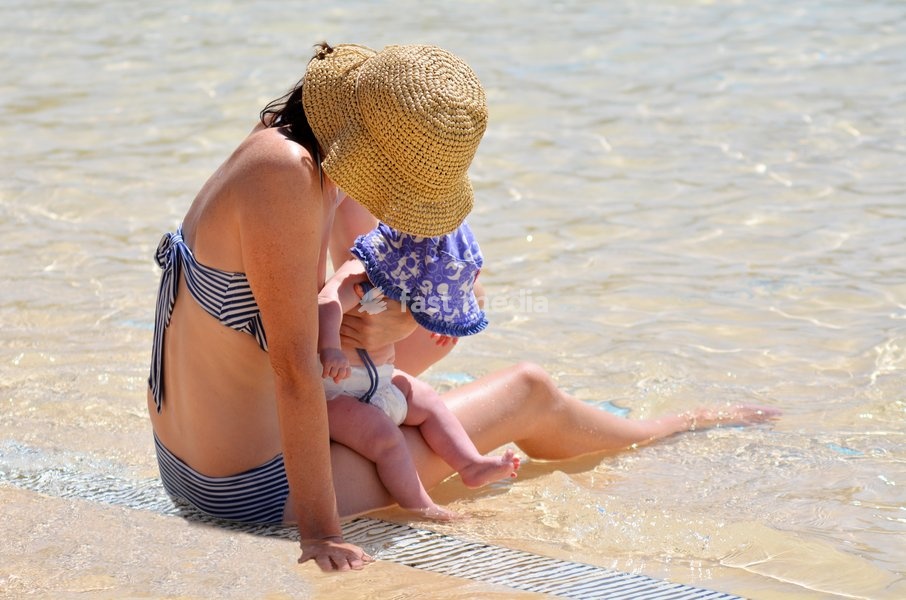 Young mother and her infant baby having fun in water pool.Concept photo with copy space