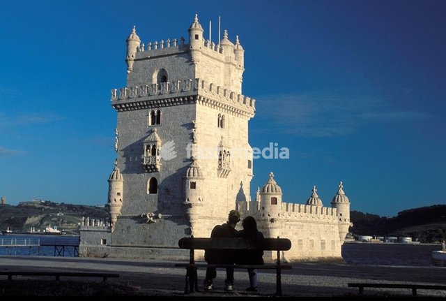 Lisbon, romantic couple sitting in front of the Belem castle tower