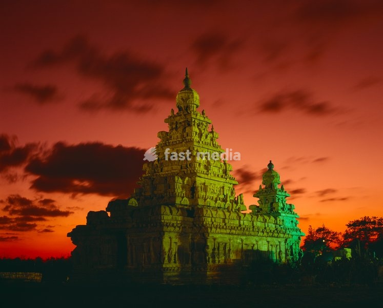 Shore Temple. Tower floodlit at dusk with dramatic orange sky and clouds