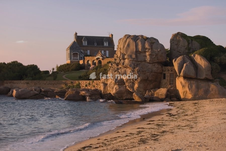 Beach house built behind rocks, Tregastel, Cote de Granit Rose, Cotes d'Armor, Brittany, France, Europe