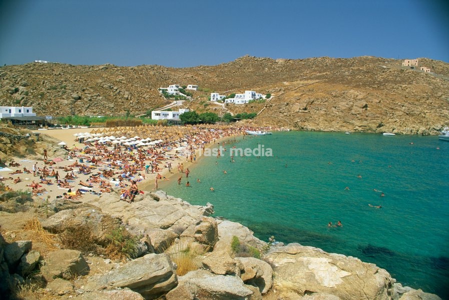 Tourists on the Super Paradise beach with small houses in the background, on Mykonos, Cyclades Islands, Greek Islands, Greece, Europe