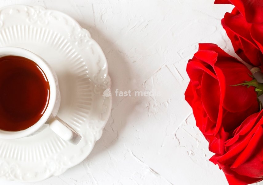 Cup of tea and red roses, top view, copy space