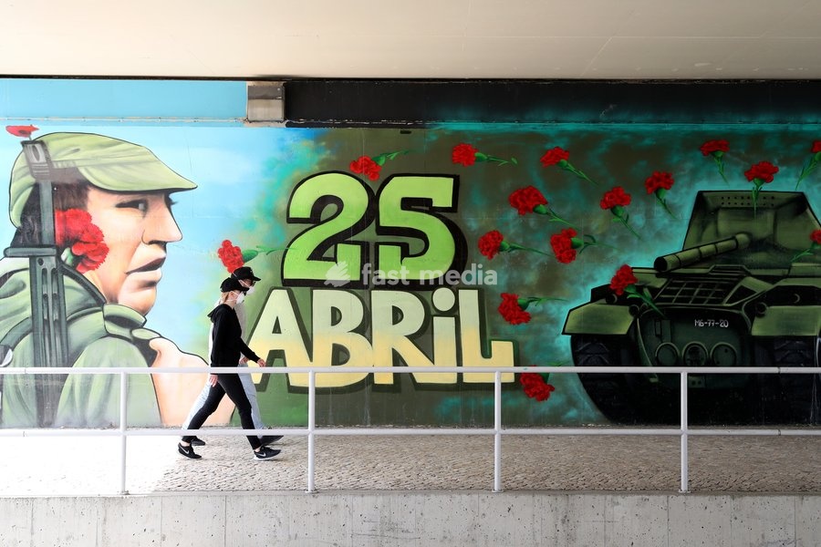 (200425) -- LISBON, April 25, 2020 () -- People wearing face masks walk past a wall with graffiti marking the 46th anniversary of the Carnation Revolution in Lisbon, Portugal, on April 25, 2020. A celebration marking the Carnation Revolution that overthrew the dictatorship and instituted democracy…