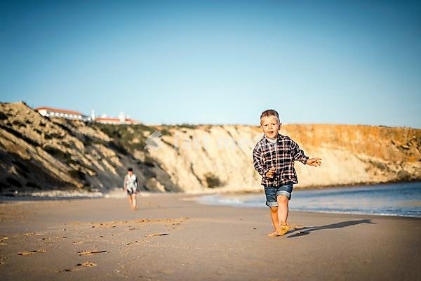 The small boy happily running on the beach by sunset, Algarve, Portugal