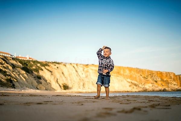 Small boy throwing stones on the beach by the sunset, Portugal