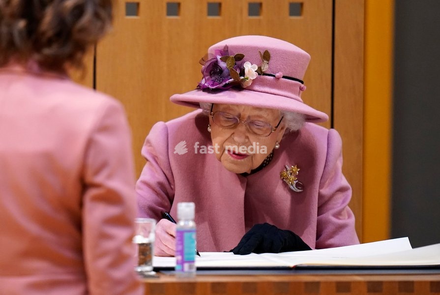 Queen Elizabeth II signs a commemorative parchment in the Senedd inside the Siambr (Chamber) during the ceremonial opening of the Sixth Senedd in Cardiff. Picture date: Thursday October 14, 2021
