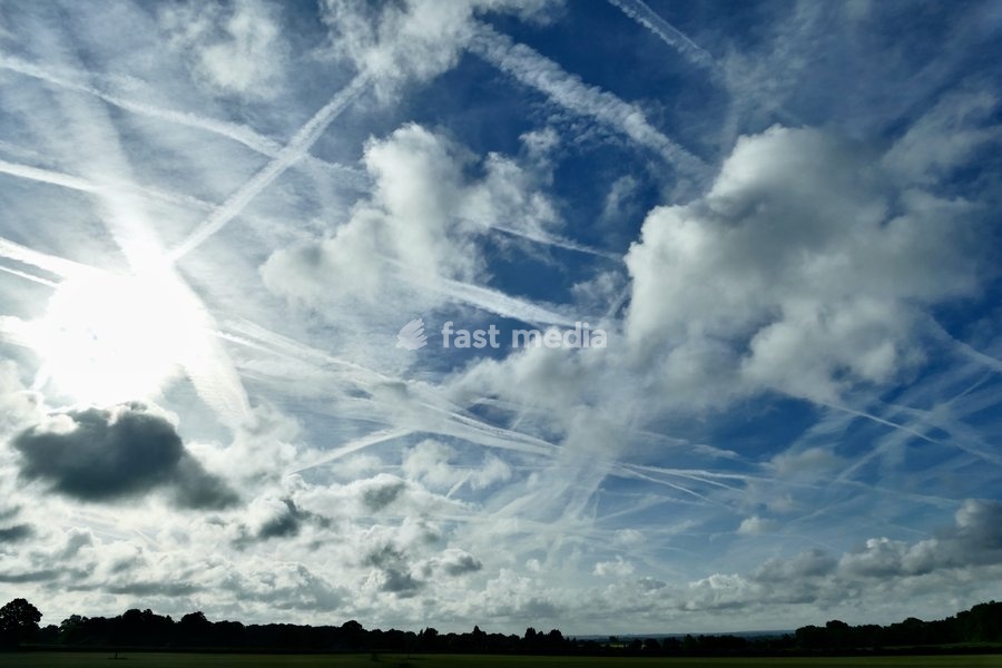 The early mornings sky is a mix of bubbling white clouds and aeroplanes contrails