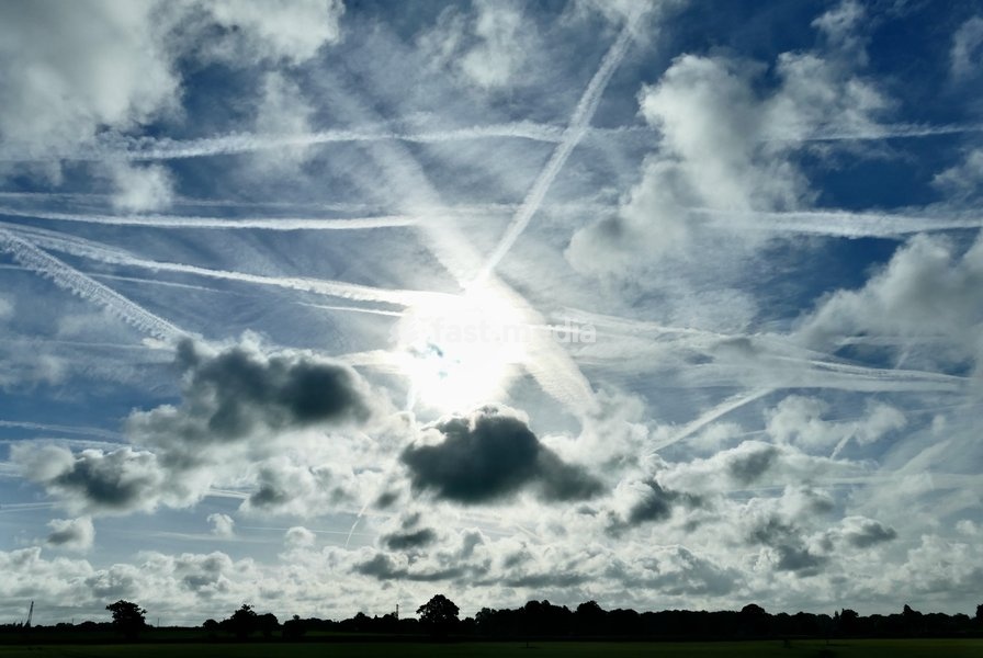 The early mornings sky is a mix of bubbling white clouds and aeroplanes contrails