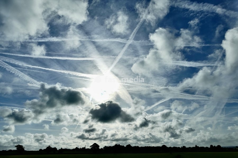 The early mornings sky is a mix of bubbling white clouds and aeroplanes contrails