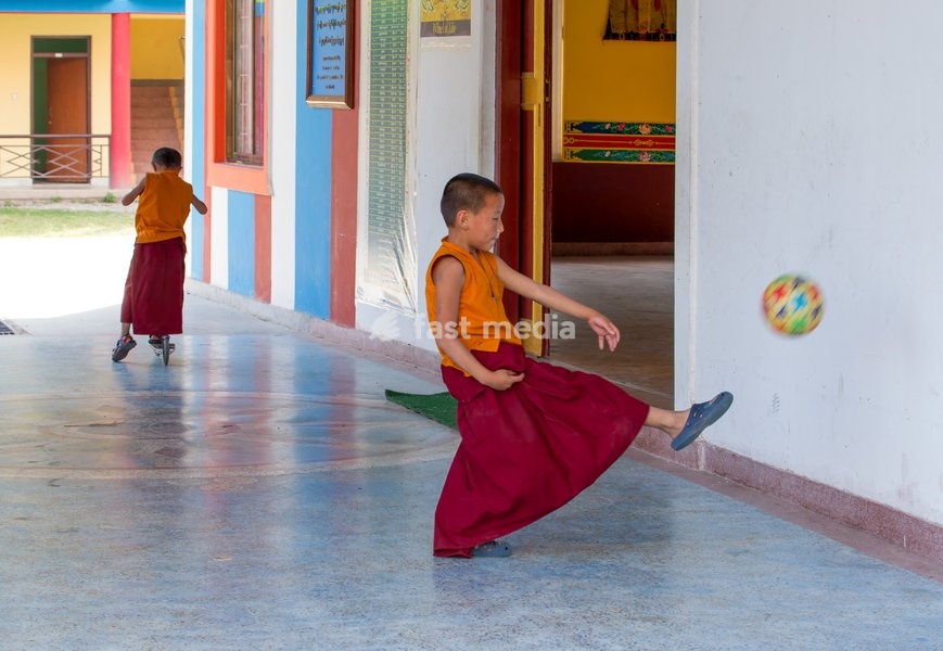 A young Buddhist monk kicks a soccer ball at the Pema Tsal Sakya Monastery near Pokhara, Nepal. Behind is another boy riding a razor scooter