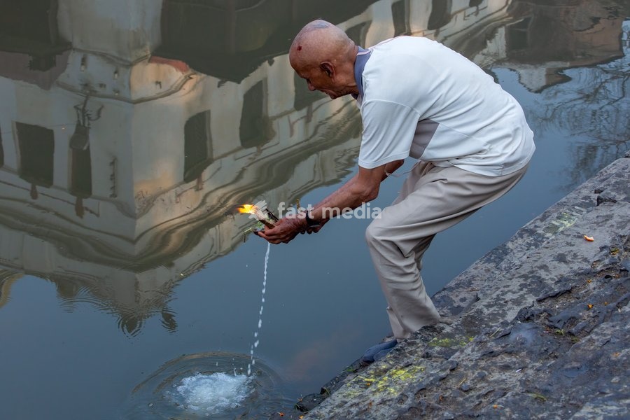 A Hindu man makes a religious offering in the Bagmati River by the Pashupatinath Temple complex, Kathmandu, Nepal